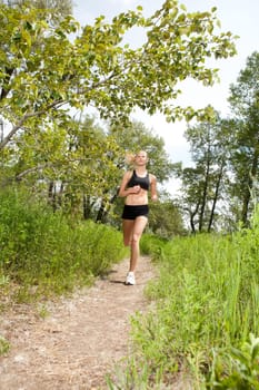 Young woman jogging outdoors in summer on trail