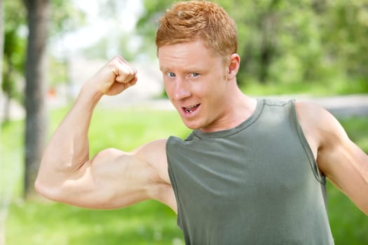 Young muscular man showing his biceps against blur background