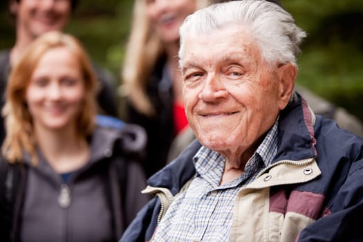 A portrait of an elderly man with young people in the background