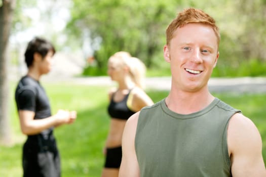 Man smiling and looking at camera while friends talking in the background