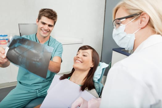 Smiling male dentist explaining the details of x-ray to a beautiful female patient