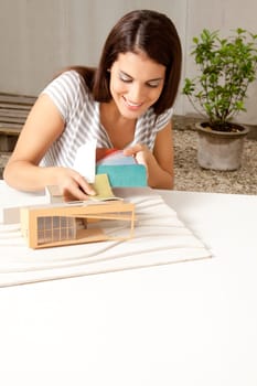 A young female architect testing a color swatch on a model house