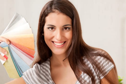 A woman looking at the camera holding a set of color swatches
