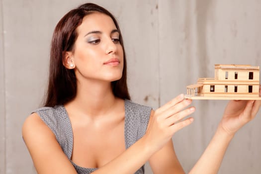 A young female architect or designer looking at a rough house model