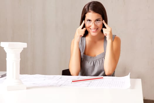 A female architect sitting at a desk with blue prints - room for copy space