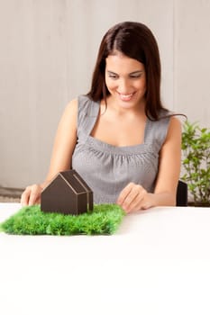 A happy professional woman looking at a model house with grass