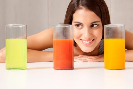 A woman looking at three science beakers filled with colored liquid