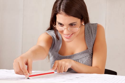 A female architect with a scale ruler measuring blueprints