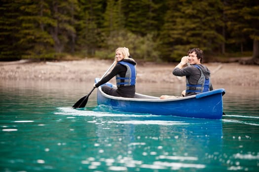 A man and woman paddling in a canoe on a lake