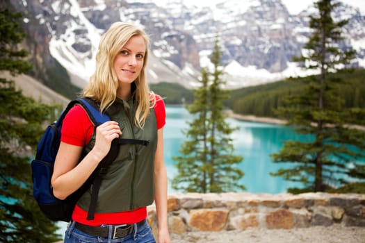 A portrait of a woman hiking on a mountain path near a lake