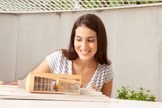 A female architect looking at a model house