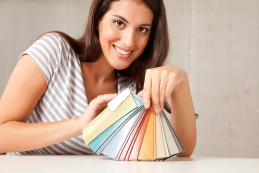 A young female interior designer displaying a group of color swatches.  Sharp focus on swatches
