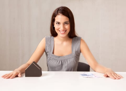 A conceptual housing market shot, a woman with model house and Euro money