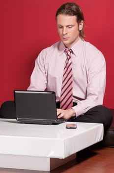 Concentrated businessman using a laptop while sitting on a floor