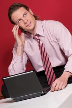 Smart businessman talking over the cellphone with laptop on the table