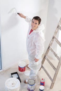 Portrait of an smiling workman painting the wall with a roller