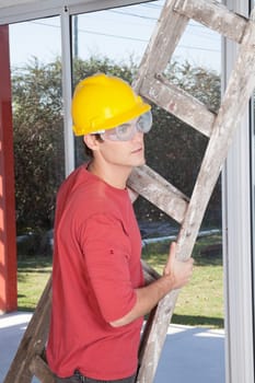 Male construction worker holding ladder in hand