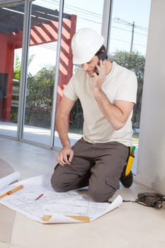 Architect working on blueprint while talking on cellphone