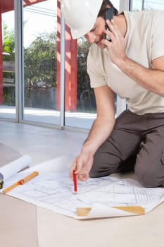 Architect working on blueprint and talking on cellphone