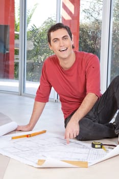 Portrait of happy smiling man pointing at blueprint of paperwork