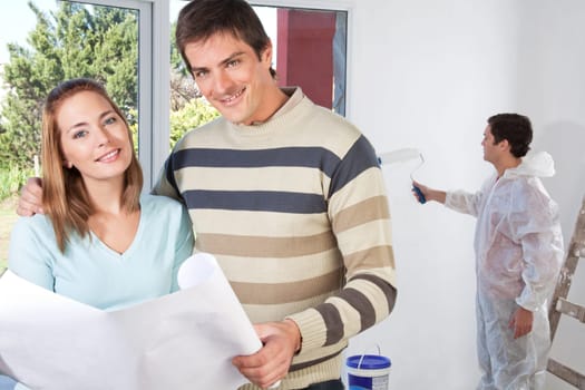 Portrait of happy couple together while painter painting the wall