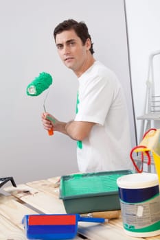 Portrait of casual man holding a roller paint brush in his hand