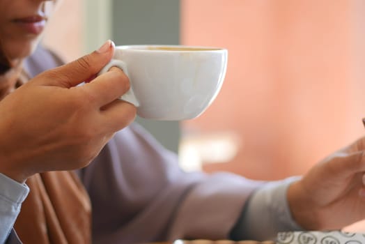 A person savors a hot drink while seated peacefully indoors.