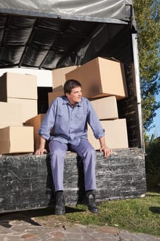 Thoughtful man sitting in the truck with pile of boxes behind him