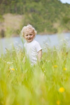 A young happy child walking through tall grass looking at the camera