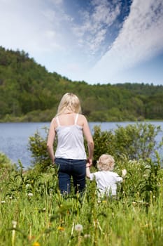 A mother walking in a meadow with a young toddler son