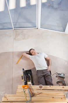 Man laying on ground with home improvement tools