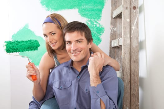 Beautiful young couple sitting together with color roller at home
