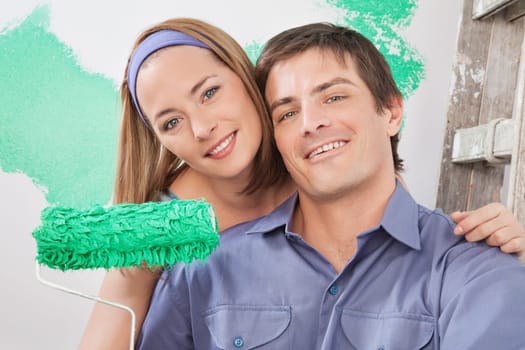 Close-up portrait of young smiling couple with paint roller