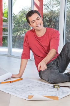 Young engineer smiling and pointing at blueprint
