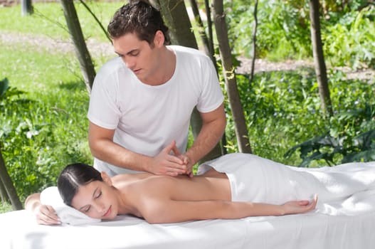 Woman receiving massage outdoors from professional masseuse