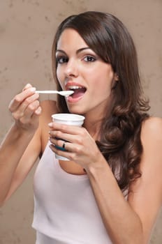 Portrait of young beautiful woman eating yogurt