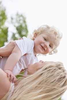 Portrait of baby boy playing with mother in park