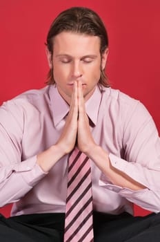 Close-up of a businessman with hands clasped and eyes closed in prayer posture