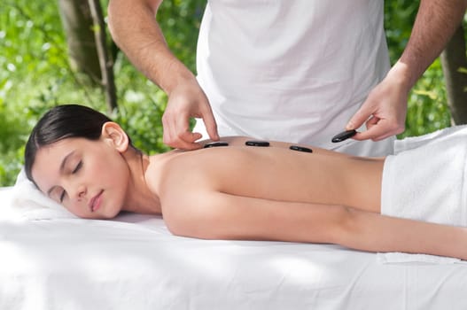 Young woman getting a hot stone massage at spa salon