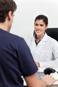 Young female doctor talking to the patient in her office
