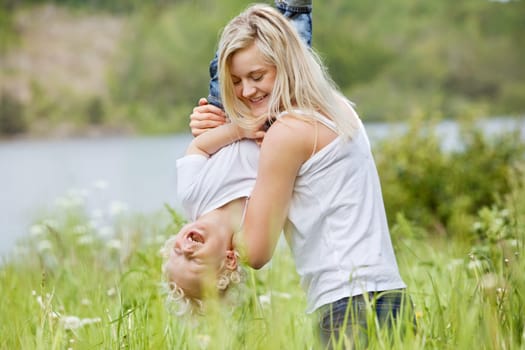 Playful woman in park playing with her laughing son