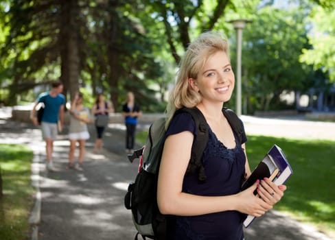 Portrait of a happy university girl walking to class outdoors