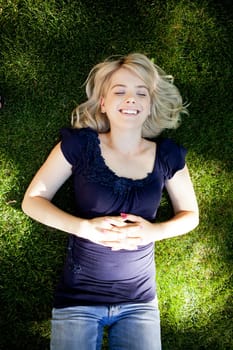 Smiling attractive student laying on grass