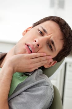 Young man holds his mouth in pain