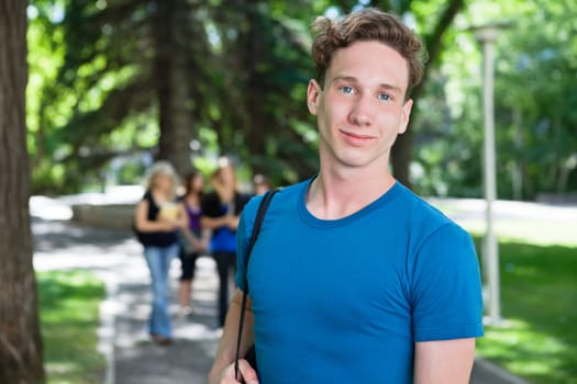 Portrait of young male smiling while his classmates walking in the background