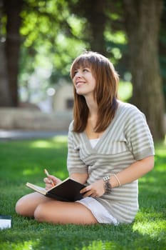 Thoughtful college student looking away while holding book