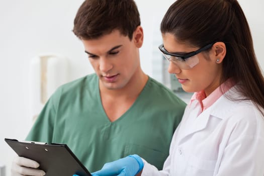 Female dentist showing something to her colleague on clipboard