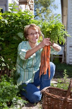 Senior woman holding fresh carrots and smiling