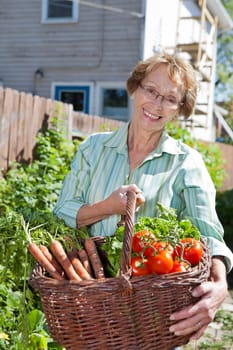 Portrait of beautiful senior woman holding basket filled with vegetables
