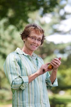 Portrait of smiling senior woman text messaging in park